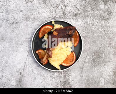 Pattes de canard rôties avec purée de pommes de terre sur une assiette ronde sur fond sombre.Vue de dessus, plan d'appartement Banque D'Images