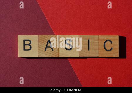 Basique, mot en lettres de l'alphabet en bois isolées sur fond rouge Banque D'Images