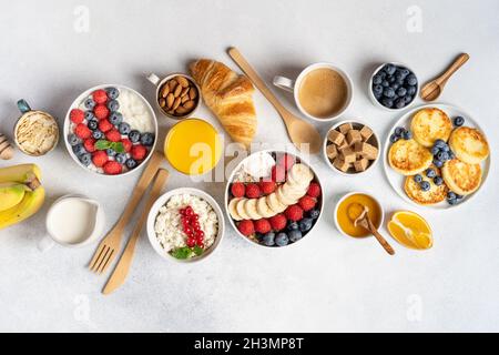 Petit déjeuner servi le matin : crêpes, porridge, fromage cottage, granola, muesli,jus d'orange, thé, café, fruits et baies. Banque D'Images