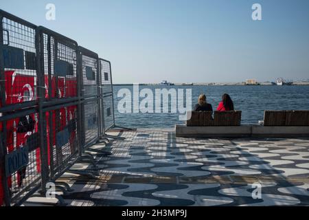 Izmir, Turquie.29 octobre 2021.Le jour de la République est un jour férié en Turquie commémorant la proclamation de la République de Turquie, le 29 octobre 1923.Deux femmes assises sur un banc à Kordon, dans le district d'Alsancak, à côté de la clôture de police.Il y a un concert dans la nuit pour la célébration, pour cette raison, la zone est protégée par des clôtures de police et l'entrée est après la ligne de sécurité.(Image de crédit : © Uygar Ozel/ZUMA Press Wire) Banque D'Images