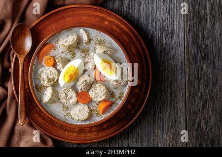 Soupe de seigle fermentée à polir Zurek avec kielbasa blanc poli traditionnel ou saucisse avec marjolaine, œufs durs servis sur un bol en argile avec un bois Banque D'Images