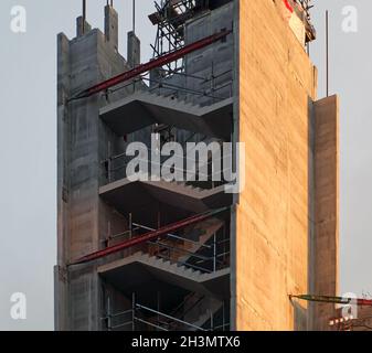 Vue verticale d'une grue sur le dessus d'un grand chantier de construction avec un cadre en béton contre un ciel bleu ensoleillé Banque D'Images