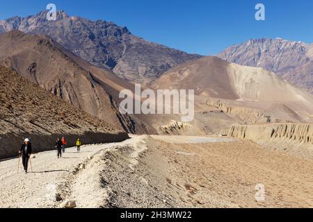 Kagbeni, district de Mustang, Népal - 19 novembre 2016 : Muktinath Sadak.Un groupe de touristes avec des bâtons de randonnée pédestre le long de la route à Muktinath. Banque D'Images