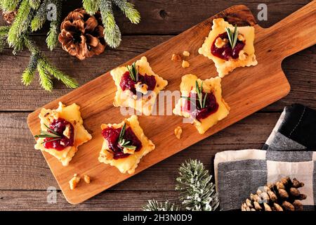 Hors-d'œuvre en forme d'étoile de Noël avec canneberges et brie cuite au four.Vue en hauteur sur une table de service sur fond de bois. Banque D'Images