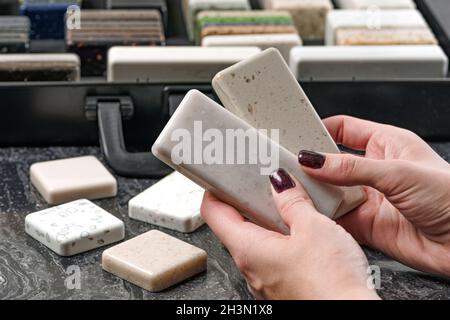 Échantillons de matériel pour le plan de travail.Les femmes choisissent des éléments intérieurs pour la rénovation.Échantillons de pierre acrylique dans les mains. Banque D'Images