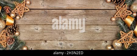 Double bordure de Noël en ruban doré et décoration avec branches d'arbre.Vue en hauteur sur un arrière-plan de bannière en bois rustique.Copier l'espace. Banque D'Images
