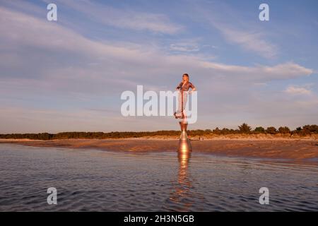 Modèle féminin sur un piédestal doré à la plage Banque D'Images