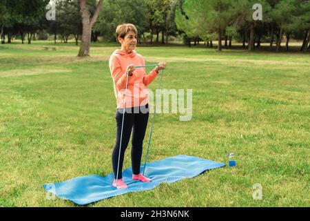 Femme senior faisant pilates entraînement routine en plein air au parc de la ville - Focus sur le visage Banque D'Images
