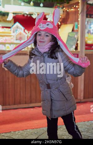 Vue nocturne d'une fille souriante avec un chapeau rose avec les oreilles illuminées à Noël à Tolède, Espagne Banque D'Images