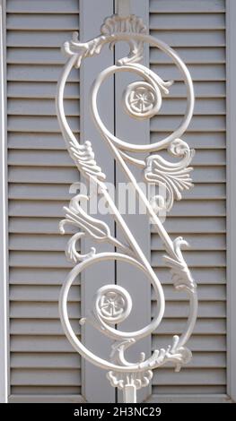 Fer forgé sur un balcon devant quelques volets en bois peint en blanc sur une maison méditerranéenne. Détails architecturaux, décoration en fer sur la clôture. Banque D'Images