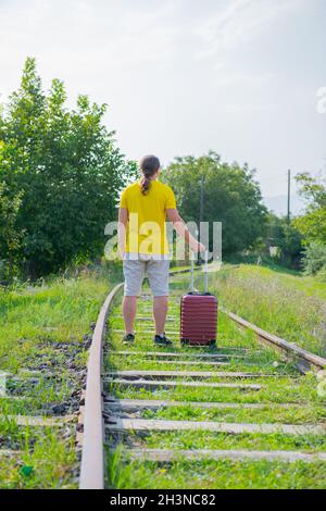une personne marche sur les rails avec une valise Banque D'Images