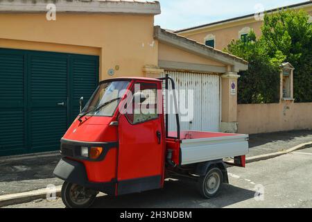 Une voiture d'APE Piaggio rouge garée dans une rue du village de pêcheurs en été, San Vincenzo, Livourne, Toscane, Italie Banque D'Images