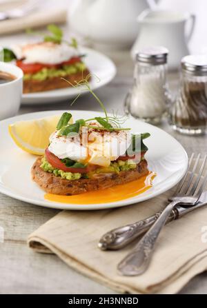 Petit déjeuner. Les meilleurs oeufs Benoît sur une tranche de pain de céréales grillé avec guacamole et épinards Banque D'Images