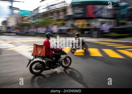 Kuala Lumpur, Malaisie.29 octobre 2021.Un pilote de livraison de nourriture passe devant une intersection près d'un quartier commerçant de Kuala Lumpur.Crédit : SOPA Images Limited/Alamy Live News Banque D'Images