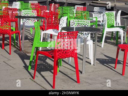 Chaises et tables de café en plein air colorées sur le thème italien dans la rue en plein soleil d'été dans les couleurs rouge vert et blanc Banque D'Images