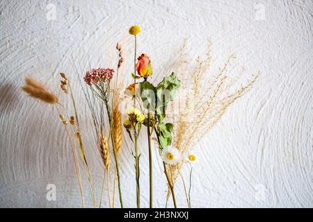 Bouquet de fleurs sèches dans une assiette en bois contre un mur blanc Banque D'Images