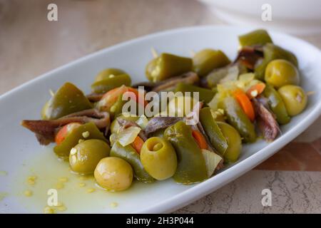 Hors-d'œuvre épicés avec olives vertes, anchois et jalapeños sur l'assiette.En-cas traditionnel basque gildas pintxos Banque D'Images