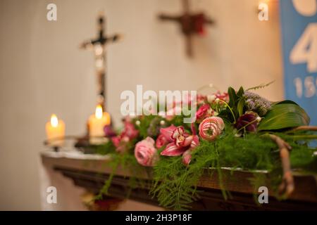 Intérieur d'une église catholique romaine avec décoration polychrome de l'autel et des fleurs, avec une croix hors foyer avec Jésus C. Banque D'Images