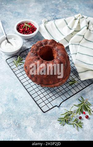 Gâteau au chocolat sur une grille métallique, sucre en poudre et canneberges dans des bols Banque D'Images