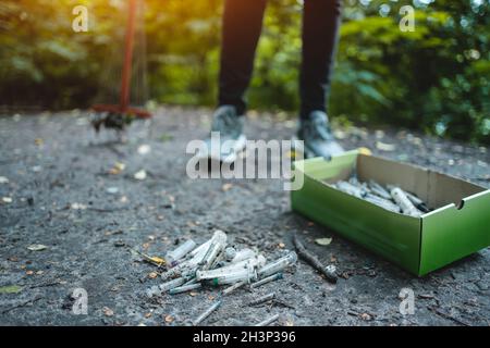 volontaire nettoyant le parc à partir de la seringue utilisée par les accros de drogue Banque D'Images