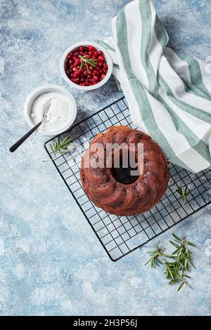 Gâteau au chocolat sur une grille métallique, sucre en poudre et canneberges dans des bols Banque D'Images