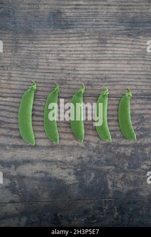 petits pois fraîchement cueillis, de gros à smal, sur une table à manger en bois, concept de simples ingrédients naturels sains Banque D'Images