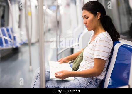 Femme lisant un livre dans le métro Banque D'Images