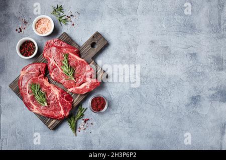 Deux steaks de bœuf Black Angus de viande fraîche brute, Rib Eye, Denver, sur planche à découper en bois. Banque D'Images