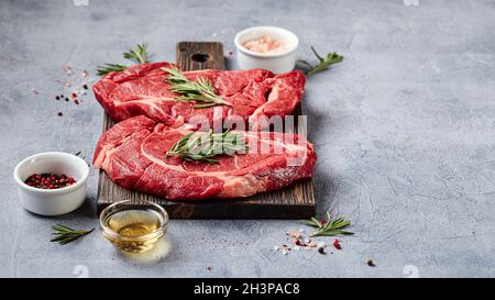 Deux steaks de bœuf Black Angus de viande fraîche brute, Rib Eye, Denver, sur planche à découper en bois. Banque D'Images