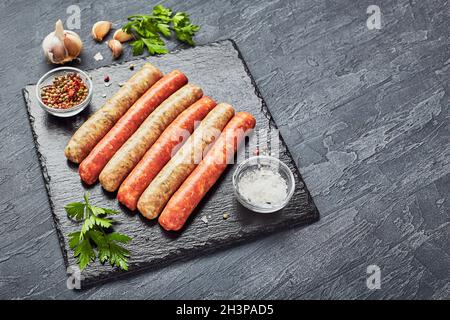 Bouchers crus saucisses sur ardoise avec herbes.Vue de dessus Banque D'Images
