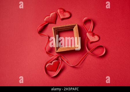 La renommée du bois et les cœurs de Saint Valentin et les décorations sur fond rouge. Banque D'Images