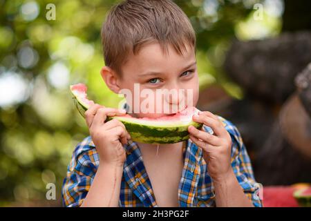 Un garçon mange une pastèque. Portrait en gros plan. Banque D'Images