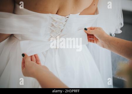 Gros plan d'une femme qui fixe le dos de la robe de la mariée à Sarajevo, Bosnie-Herzégovine Banque D'Images