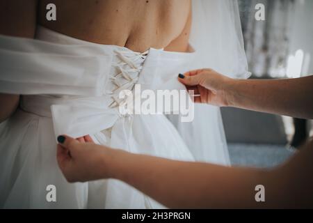 Gros plan d'une femme qui noue l'arc de la robe de mariage sur la mariée lors d'un mariage à Sarajevo Banque D'Images