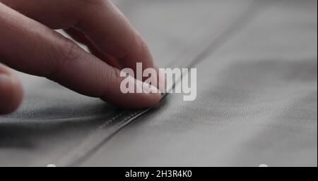 gros plan homme main vérifier couture sur cuir gris doux vêtements, photo large Banque D'Images