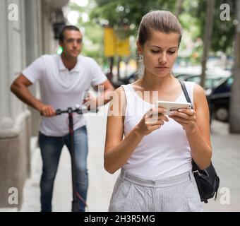 Couple utilisant un smartphone dans la rue Banque D'Images