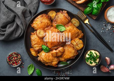 Cuisses de poulet aux oignons frits, à l'ail et au basilic frais sur fond sombre.Vue de dessus, horizontale. Banque D'Images