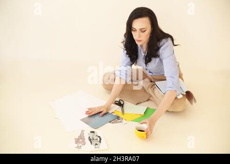 Jeune femme brunette créant sa carte de souhaits Feng Shui assis sur le sol Banque D'Images