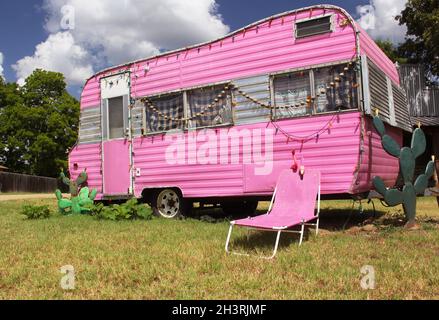 Remorque de voyage rose avec chaise et cactus, plus ciel bleu et nuages Banque D'Images