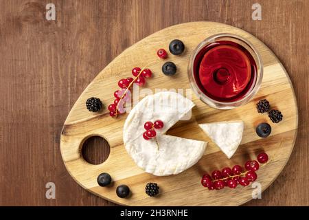 Une photo en hauteur du fromage Camembert avec un verre de vin rouge et de fruits Banque D'Images