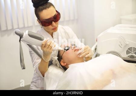 Femme traitant le visage du client au laser Banque D'Images