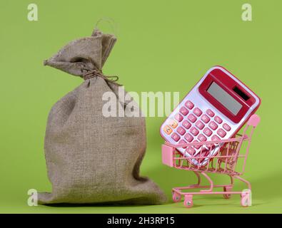 Sac en toile, calculatrice en plastique rose dans un panier en métal miniature sur fond vert Banque D'Images