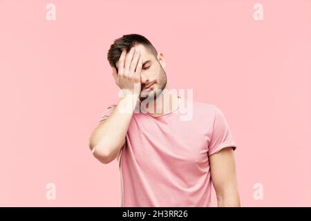 Fatigué déçu jeune homme avec visage paume geste sur fond rose Banque D'Images