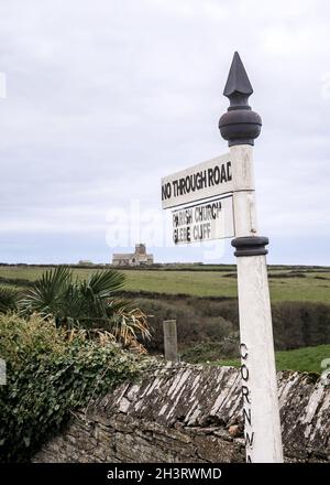 Panneau traditionnel en métal rétro blanc pointant vers le chemin de la falaise et l'église dans le village près de Glebe Cliff dans le sud-ouest de l'Angleterre de Cornwall.Belle campagne Banque D'Images