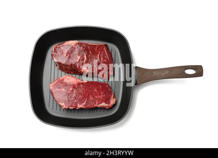 Deux morceaux de bœuf crus dans une poêle à grillades carrée noire, steaks isolés sur fond blanc Banque D'Images