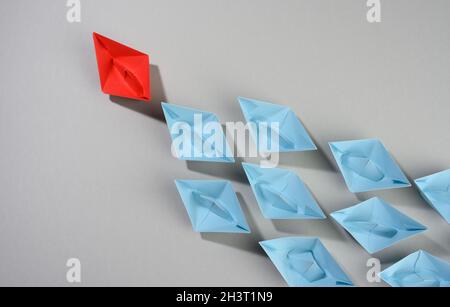 Groupe de bateaux en papier sur fond gris. Concept d'un leader fort dans une équipe, manipulation des masses Banque D'Images