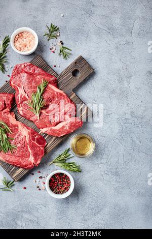 Deux steaks de bœuf Black Angus de viande fraîche brute, Rib Eye, Denver, sur planche à découper en bois. Banque D'Images