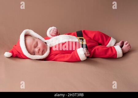 Fille de nouveau-né vêtue de costume du père noël bâillements fatigués. Banque D'Images