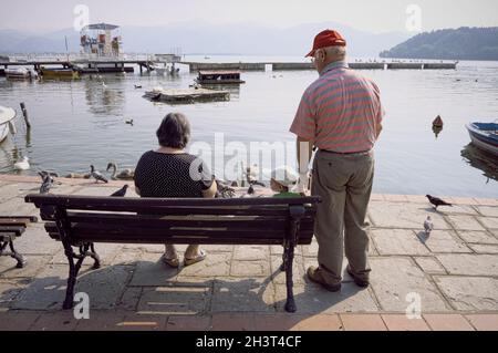 Grands-parents et petit-fils assis sur un banc au bord du lac Orestiada dans la ville grecque de Kastoria Banque D'Images