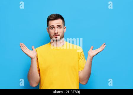 Un jeune homme confus se répand les mains sur le côté sent le doute tandis qu'il fait le choix Banque D'Images